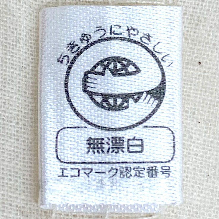 地球にやさしいものづくりにこだわった、エコマーク取得の無漂白キャンバストートバッグです。エコマークとは、原材料の調達から生産、流通、廃棄に至るまで製品のライフサイクル全体を通して環境への負荷が少なく、環境保全に役立つと認められた商品にのみ付けられる、信頼性の高い環境ラベル。このバッグはその基準をクリアした無漂白生地を使用しており、漂白加工を行わないことで余計な薬剤を使わず、生成りならではの自然な風合いと素朴な色味をそのまま生かしています。サステナブルでエシカルな暮らしを意識する方や、環境に配慮したエコバッグ・サブバッグをお探しの方にぴったりの一枚。普段使いはもちろん、ナチュラルテイストのファッションとも好相性で、ノベルティや販促品、ギフトとしてもおすすめです。地球環境にも肌にもやさしい、安心して長く使えるエコフレンドリーなアイテムをぜひお手元に。