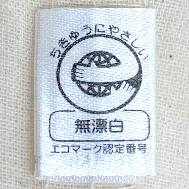 さらにこちらは、環境にやさしいエコマークを取得した無漂白アイテム。エコマークとは、生産から廃棄まで全体を通して環境への負荷が少なく、環境保全に役立つと認められた商品に付けられる環境ラベルです。漂白を行わない自然なままの素材だからこそ生まれる、やわらかな生成りの色合いと素朴な質感をお楽しみいただけます。サステナブルな暮らしを意識する方へのギフトや、ノベルティ・販促品としてもおすすめの一品です。