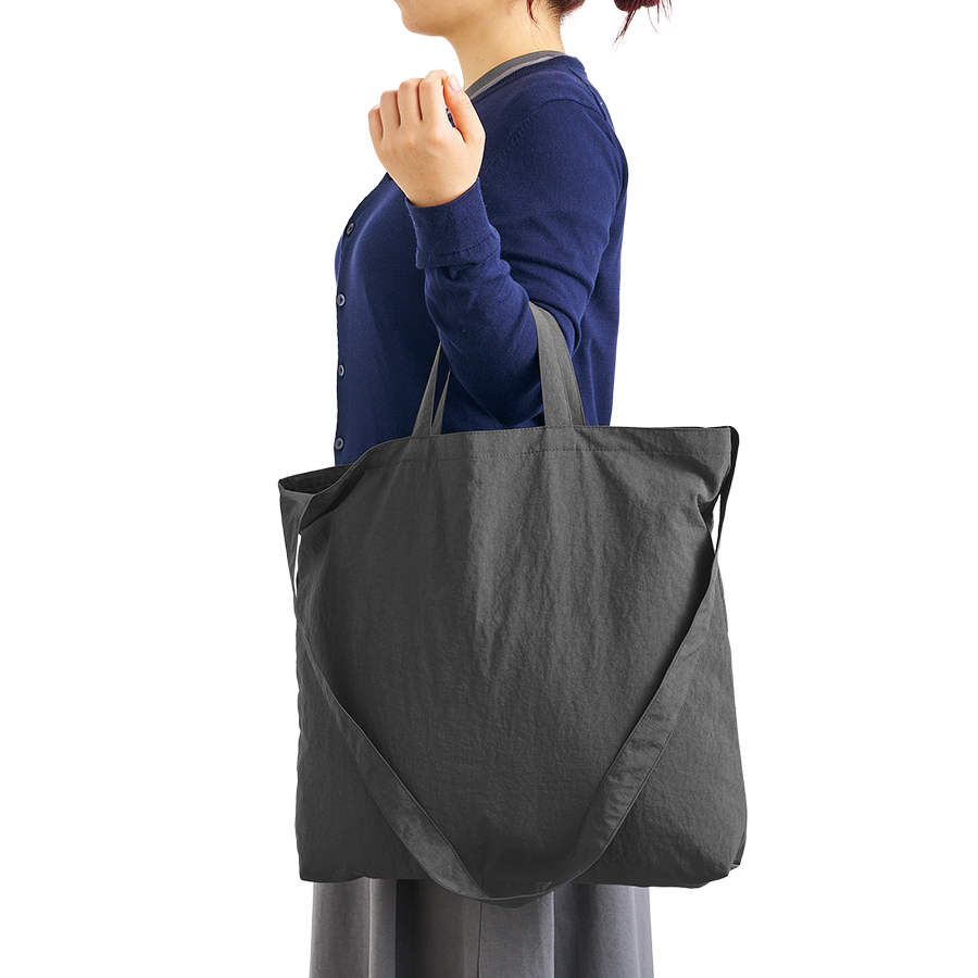 肩掛けにも手持ちにも対応する、使い勝手のよい2WAY仕様のトートバッグです。ロングハンドルでショルダーバッグのように肩掛けすれば両手が空いて通勤・通学や買い物に便利、ショートハンドルで手持ちすればすっきりとした印象に。その日の荷物量やコーディネート、シーンに合わせて持ち方を自由に切り替えられるので、デイリーユースのサブバッグやエコバッグとしても活躍します。ワッシャーナイロンの軽量素材を採用しているため、長時間の持ち歩きでも肩や腕への負担を感じにくく、旅行やレジャー、お出かけのお供にもぴったり。軽くて丈夫、そして持ち方を選べる自由さが、毎日をもっと快適にしてくれます。